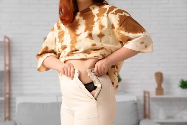 Image of woman trying to do her trousers up after pregnancy weight gain Stirling